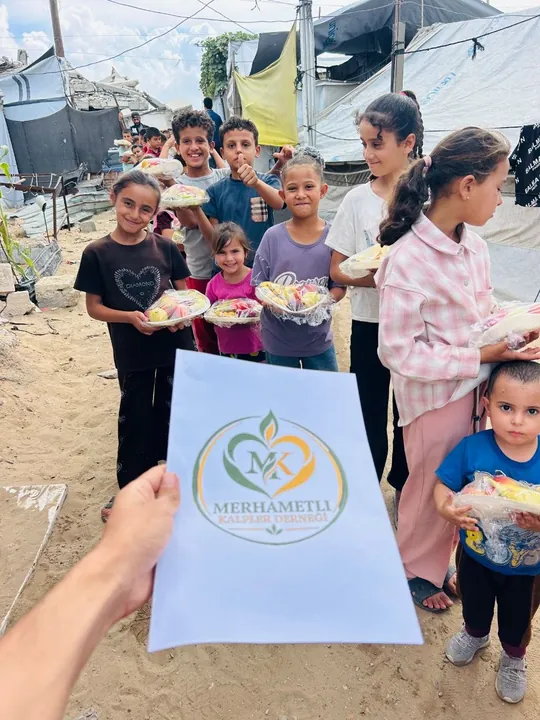 Meyve paketleriyle sıraya girmiş gülümseyen çocuklar